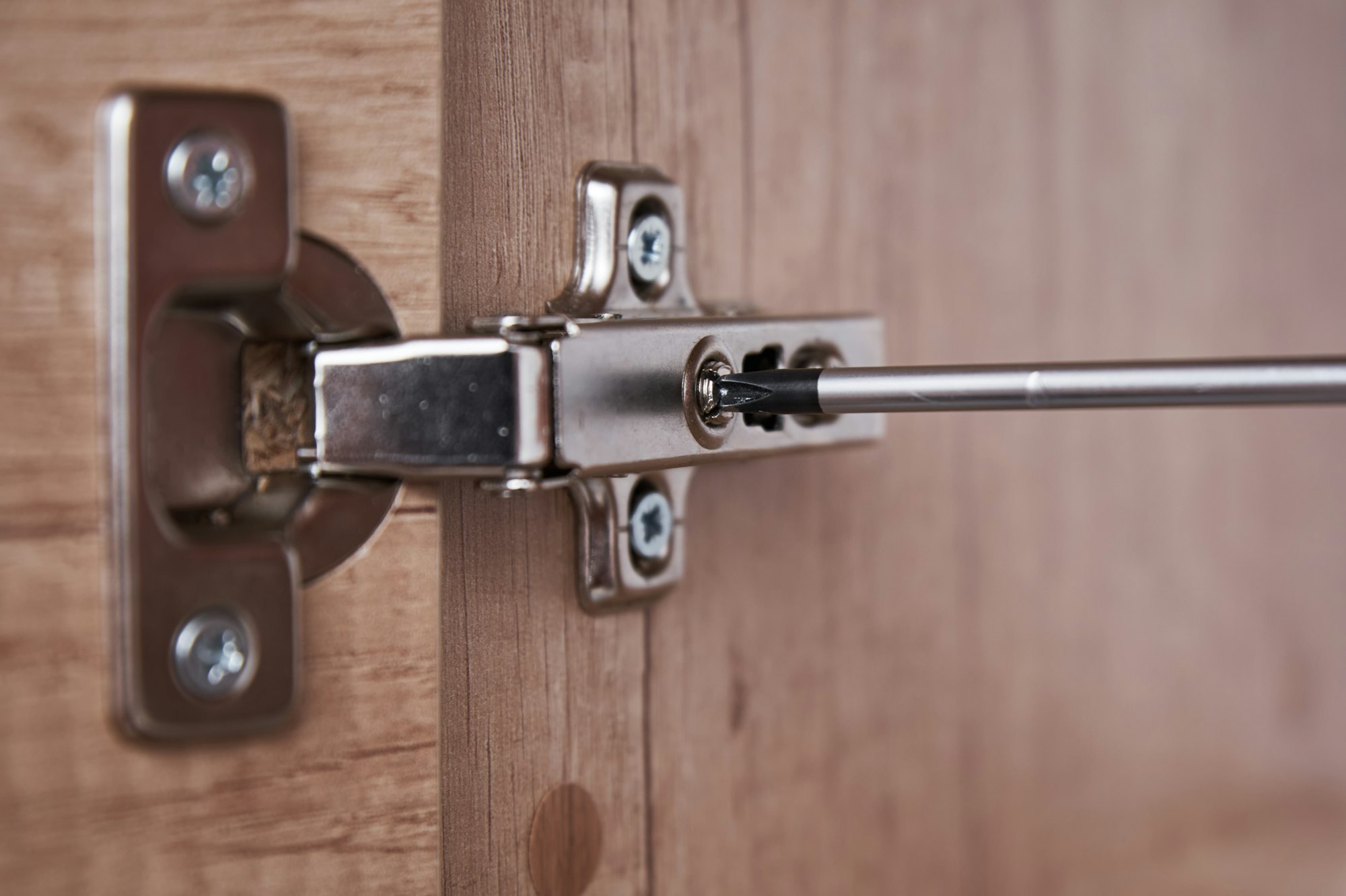 Hand screwing door hinge on kitchen cabinet